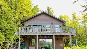 Une cabane à deux étages dotée d’un balcon, entourée d’une végétation luxuriante.