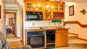 Une cuisine avec des meubles en bois, un four à micro-ondes, un four traditionnel et un lave-vaisselle.