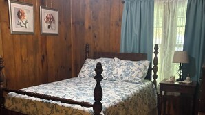 A wooden room with a bed, a nightstand, and a lamp.