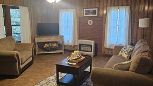 A cozy living room with two sofas, a coffee table, a fireplace, and a ceiling fan.