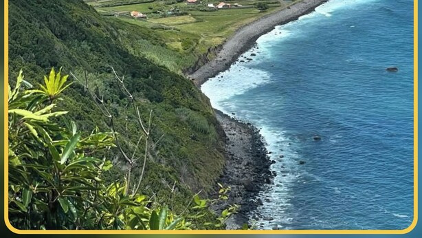 A coastal landscape with a small settlement by the sea, featuring houses and a narrow strip of land between the ocean and a hill. - Herdade das Hortênsias (São Jorge)
