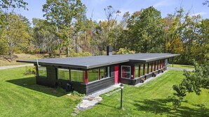 A modern building with a flat roof, large glass windows, and a red door. - Friendly Hills | Passive Home • EV Charger (Pittsfield)
