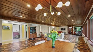 A spacious living area with a wooden ceiling, a large wooden dining table, and a modern chandelier. - Friendly Hills | Passive Home • EV Charger (Pittsfield)