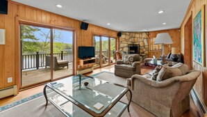 A spacious living room with a stone fireplace, a television, and a glass coffee table.