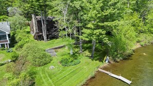 A lakeside property with a dock, a stone building, and a well-maintained lawn.