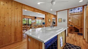 A kitchen with wooden walls, a marble countertop, and a dishwasher.