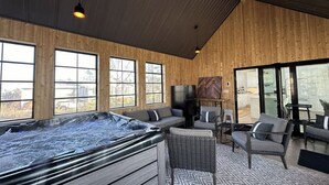 A modern interior with a hot tub, seating area, and large windows.