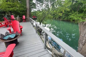 A wooden deck with red Adirondack chairs and a fire pit.
