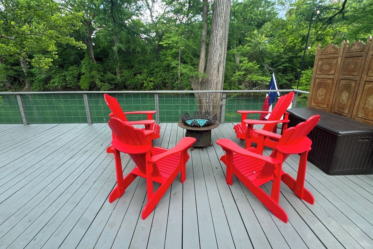Une terrasse avec des fauteuils Adirondack rouges, un foyer et un banc en bois.