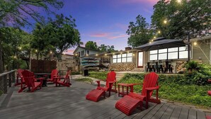 Una terrazza con poltrone Adirondack rosse, un muro in pietra e un edificio con ampie finestre.