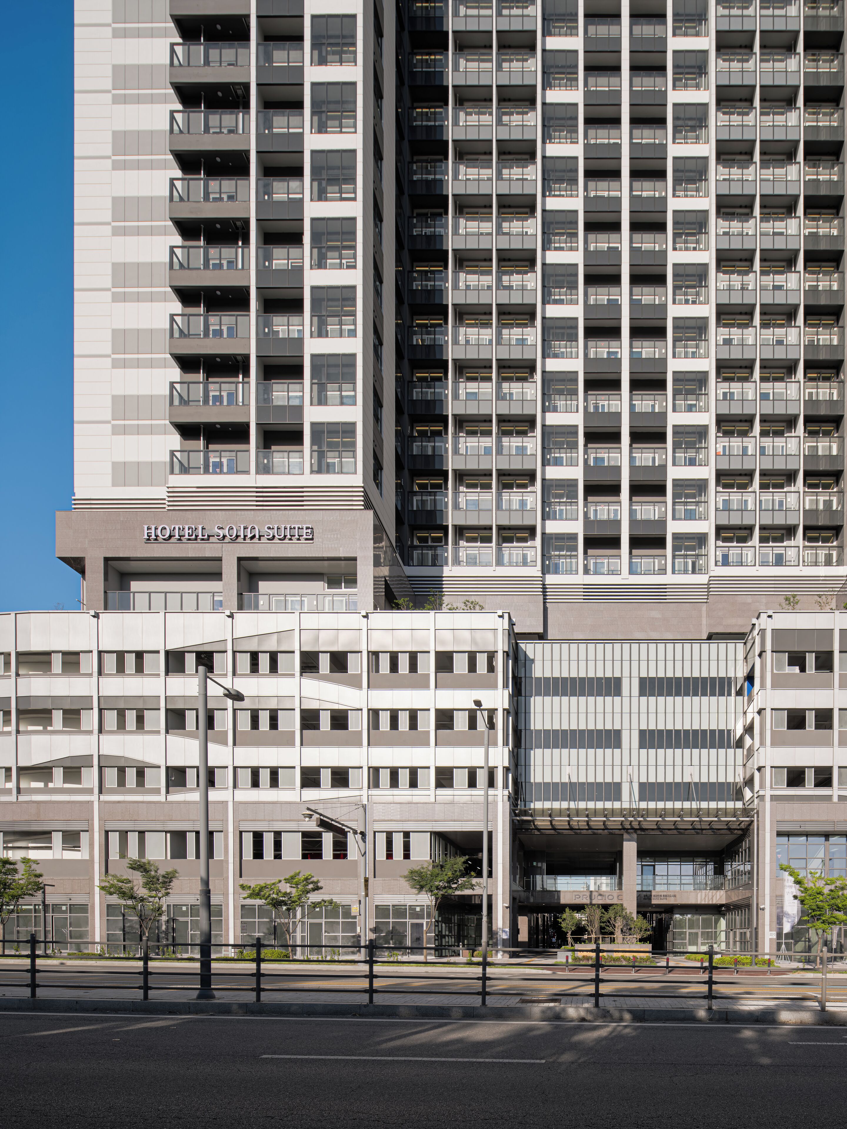 A modern hotel with multiple floors, balconies, and a clear sky.