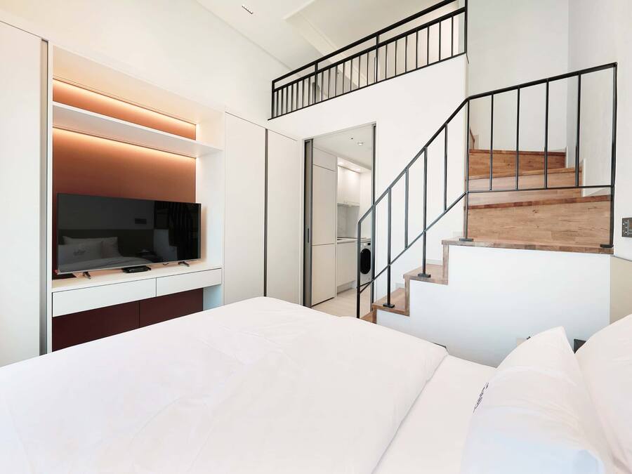 Un dormitorio moderno con una cama grande, un televisor y una escalera.