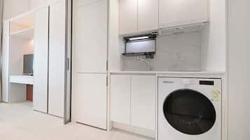 Een moderne wasserij met een voorlader wasmachine, een inbouw droger en een klein plankje boven de droger.