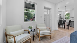 A modern living room with two armchairs, a small table with a plant, and a view of the kitchen through an open door. - Carolina Cottage Near Ft Jackson, 5Pts & Zoo! Sleeps 12-Spacious 4 bed/2.5 bath! (Columbia)