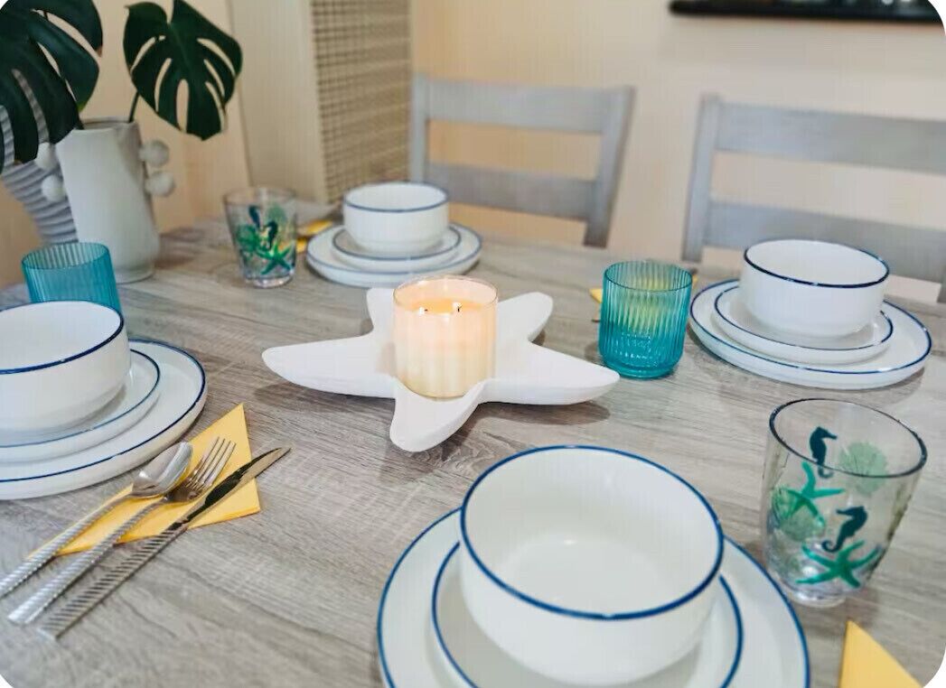A dining table set with white plates, blue rimmed bowls, and clear glassware.