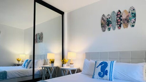 A hotel room with two beds, a large mirror, and decorative wall art.