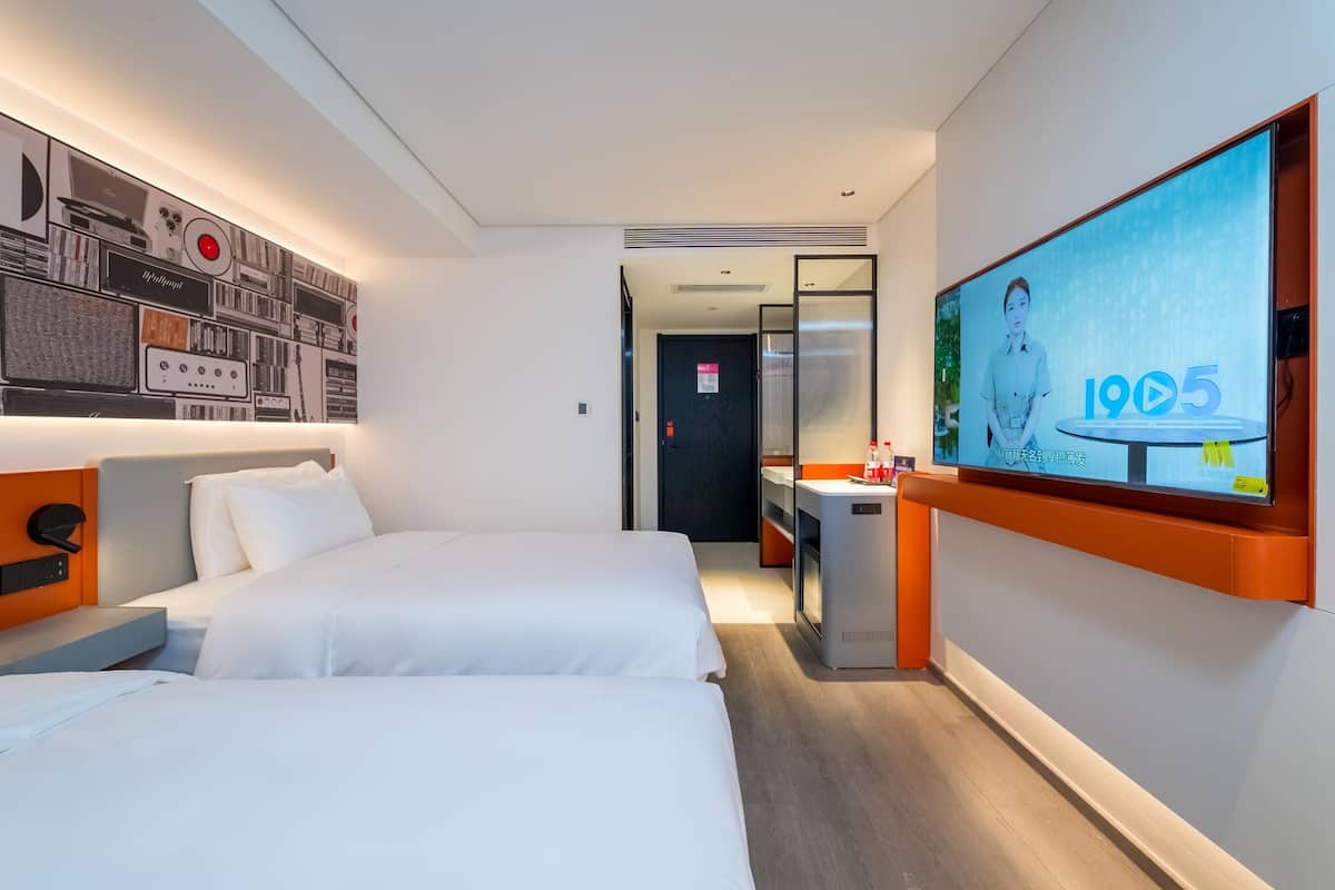 Ein Hotelzimmer mit zwei Betten, einem großen Fernsehbildschirm und einer Wand mit einem Vintage-Radiodesign.