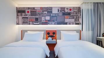 A hotel room with two beds, a headboard with a mirror, and a wall decorated with vintage audio equipment.