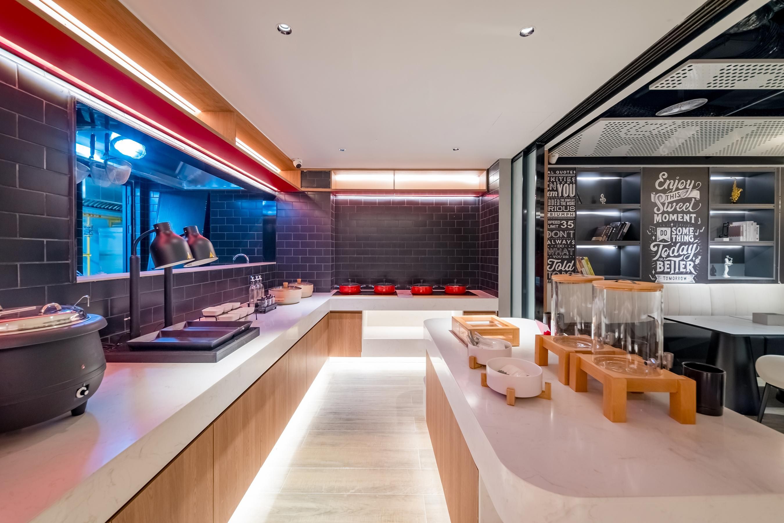 Una cocina moderna con una encimera larga, ollas rojas y una pizarra con citas motivacionales.