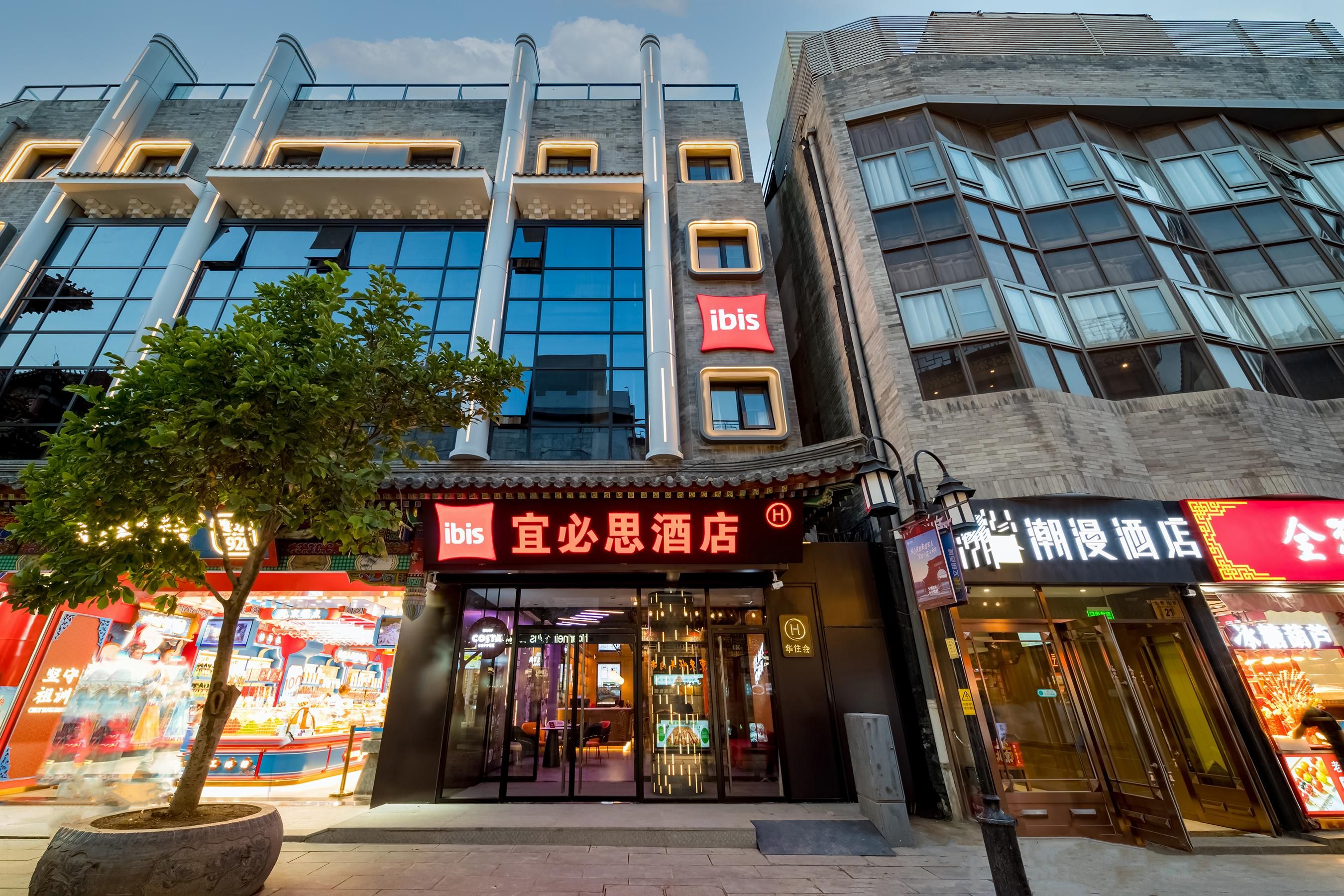 Een hotel met een moderne gevel, een opvallend ‘ibis’ bord en een traditioneel Chinees architectonisch element.