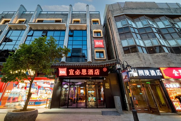A hotel with a modern facade, a prominent 'ibis' sign, and a traditional Chinese architectural element. - Ibis Hotel (Beijing)