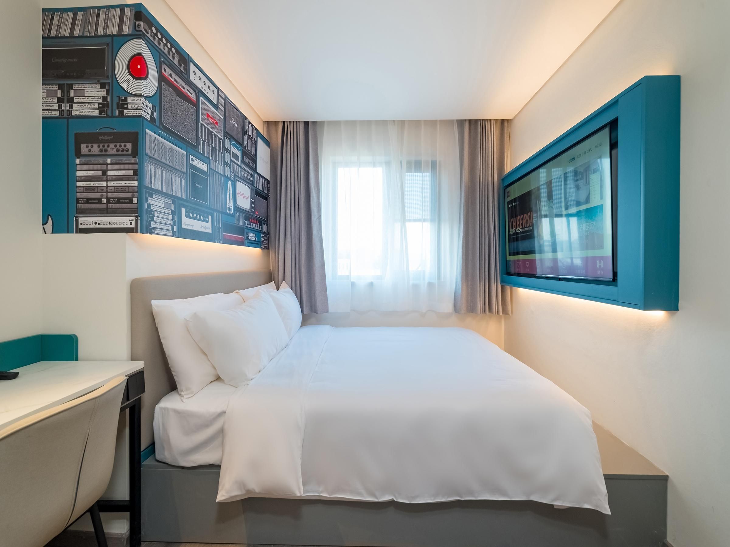 Une chambre d’hôtel moderne avec un lit bien fait, un bureau et un téléviseur fixé au mur.