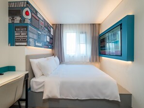 A modern hotel room with a neatly made bed, a desk, and a wall-mounted TV. - Ibis Hotel (Beijing)