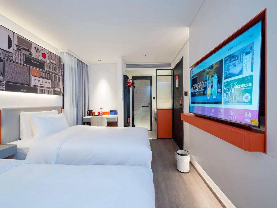 Habitación de hotel con una cama grande, un escritorio y un televisor en la pared mostrando un menú.