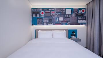 A hotel room with a bed, a nightstand with a lamp, and a wall decorated with vintage audio equipment.
