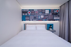 A hotel room with a bed, a nightstand with a lamp, and a wall decorated with vintage audio equipment. - Ibis Hotel (Beijing)