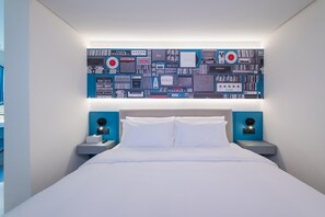 A modern hotel room with a large bed, two bedside tables, and a wall-mounted artwork featuring electronic devices. - Ibis Hotel (Beijing)