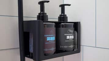 A black soap dispenser with a pump, a brown bottle of shower gel, and a black bottle of shampoo.