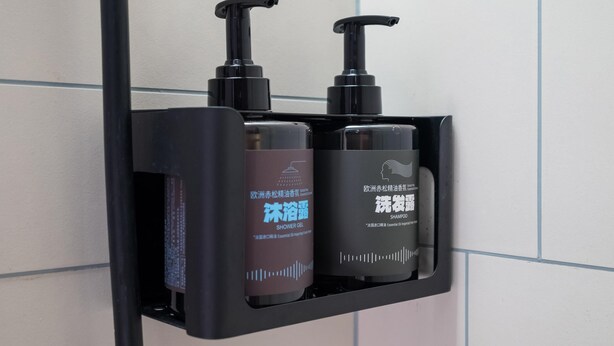 A black soap dispenser with a pump, a brown bottle of shower gel, and a black bottle of shampoo. - Ibis Hotel (Beijing)