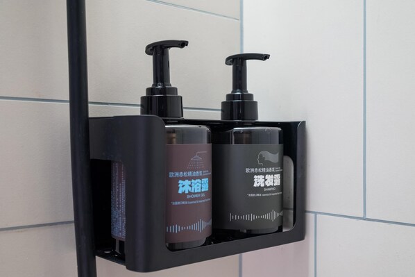 A black soap dispenser with a pump, a brown bottle of shower gel, and a black bottle of shampoo. - Ibis Hotel (Beijing)