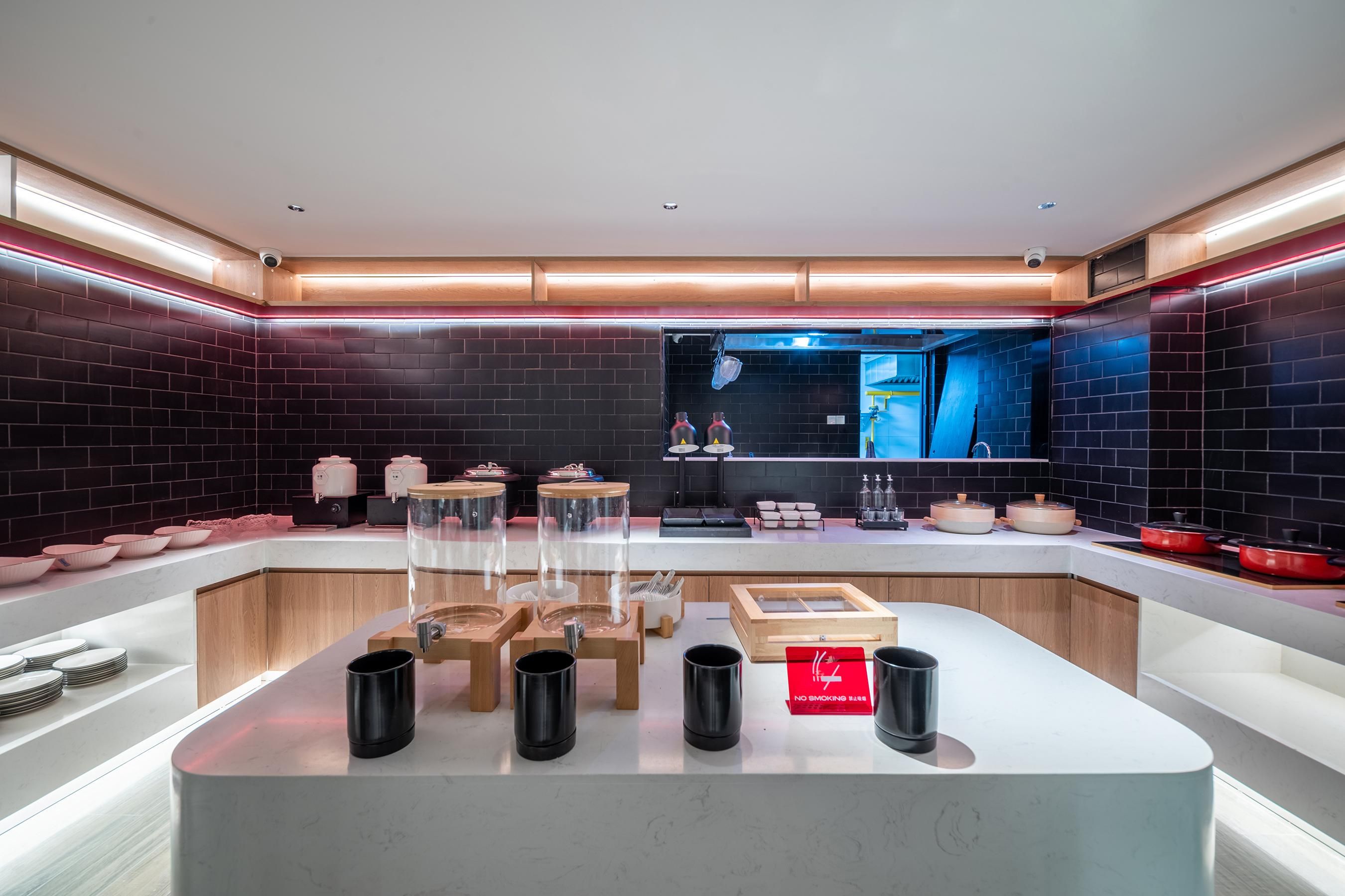 A modern kitchen with a central island, black mugs, and a 'No Smoking' sign.