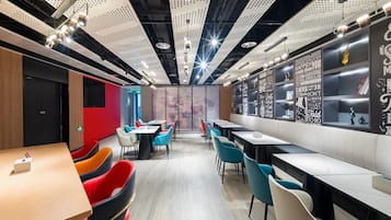 Un restaurante moderno con techos altos, paneles perforados y citas motivacionales en las paredes.
