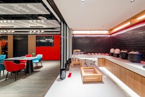A modern kitchen area with a long countertop, a glass enclosure, and various kitchen appliances. - Ibis Hotel (Beijing)