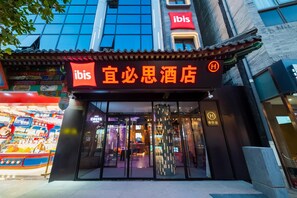 A hotel entrance with a traditional Chinese architectural style, a modern glass facade, and a prominent 'ibis' sign. - Ibis Hotel (Beijing)