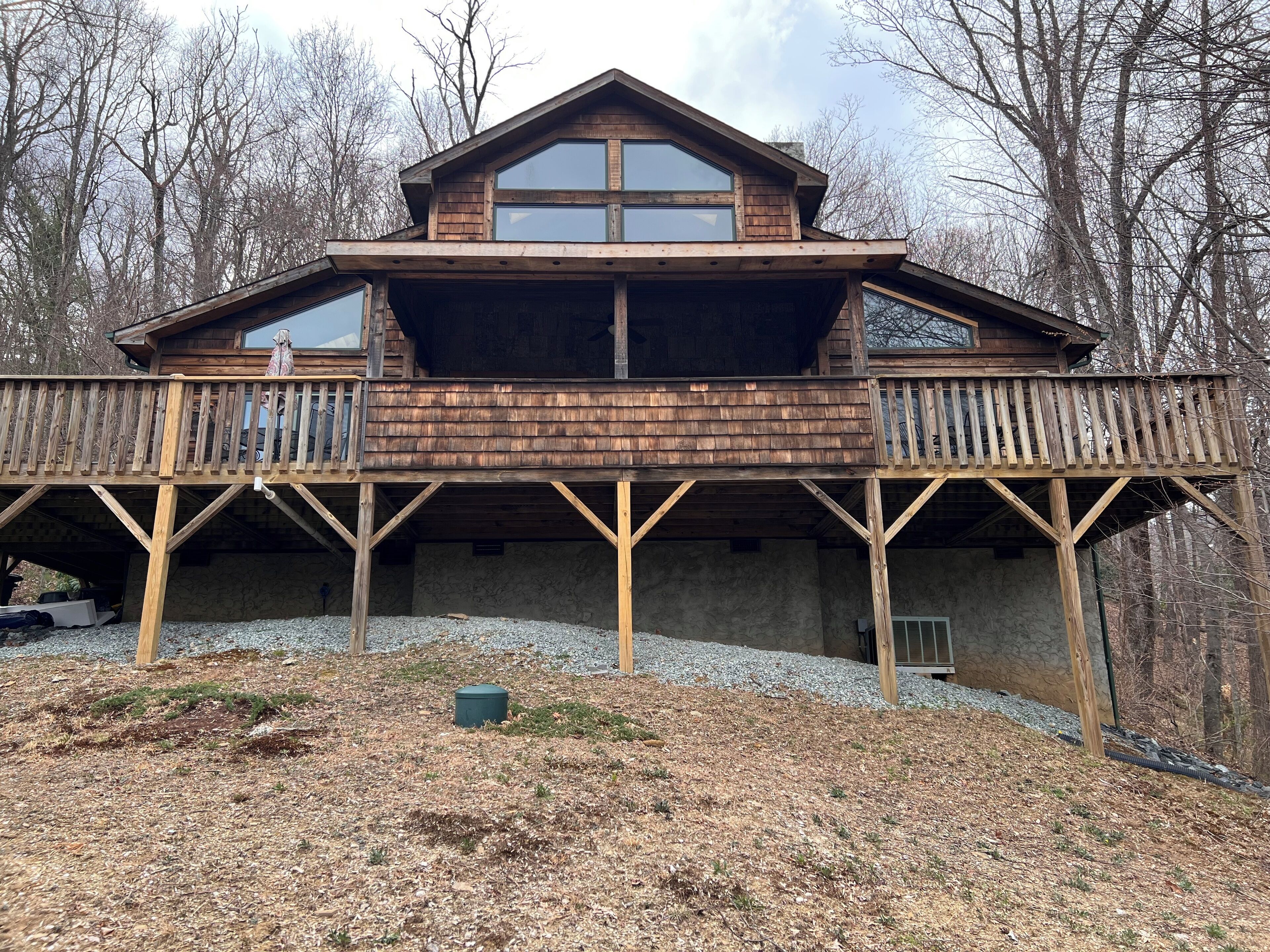 A two-story wooden cabin with a balcony and a large window.