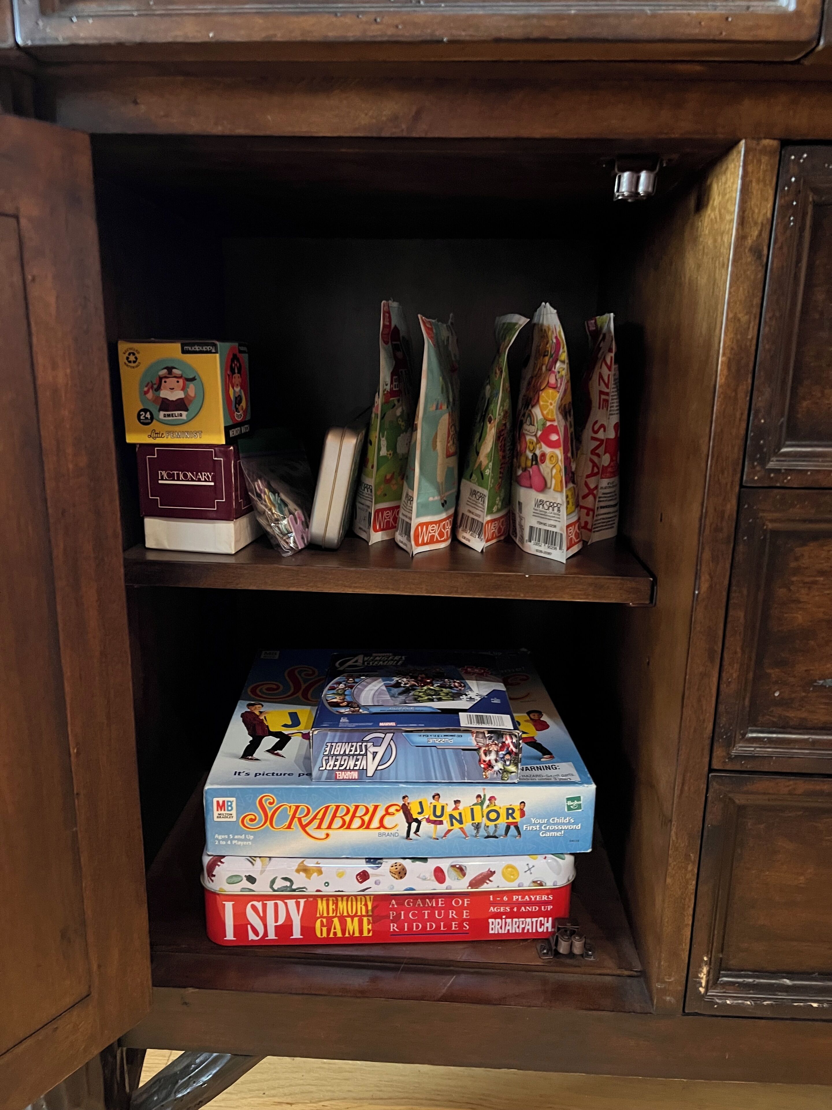 A wooden cabinet with various board games and puzzles.