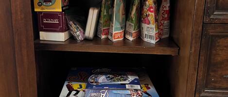 A wooden cabinet with various board games and puzzles.