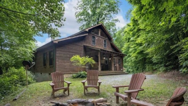 Eine rustikale Holzhütte mit Feuerstelle und Adirondack-Stühlen im Garten.