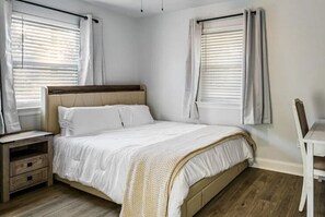 A bedroom with a bed, bedside table, and a chair.