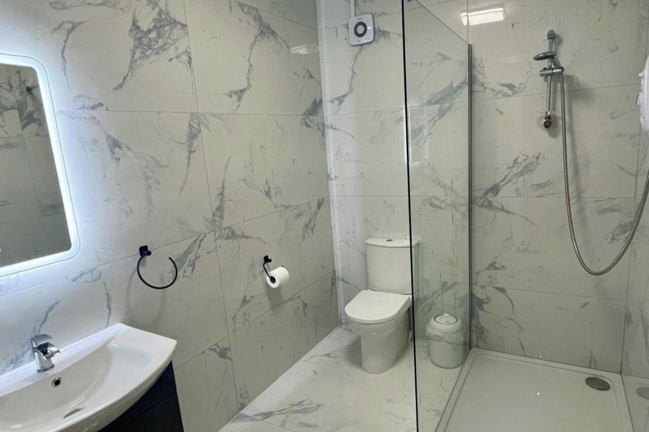Une salle de bain avec un sol en marbre, un lavabo, des toilettes et un espace douche.
