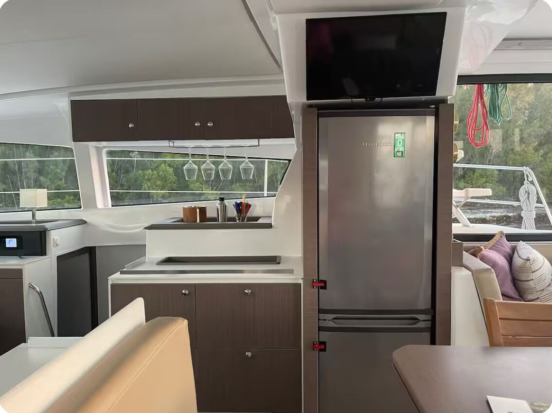 Uma cozinha compacta com geladeira, pia e janela com vista para o verde.