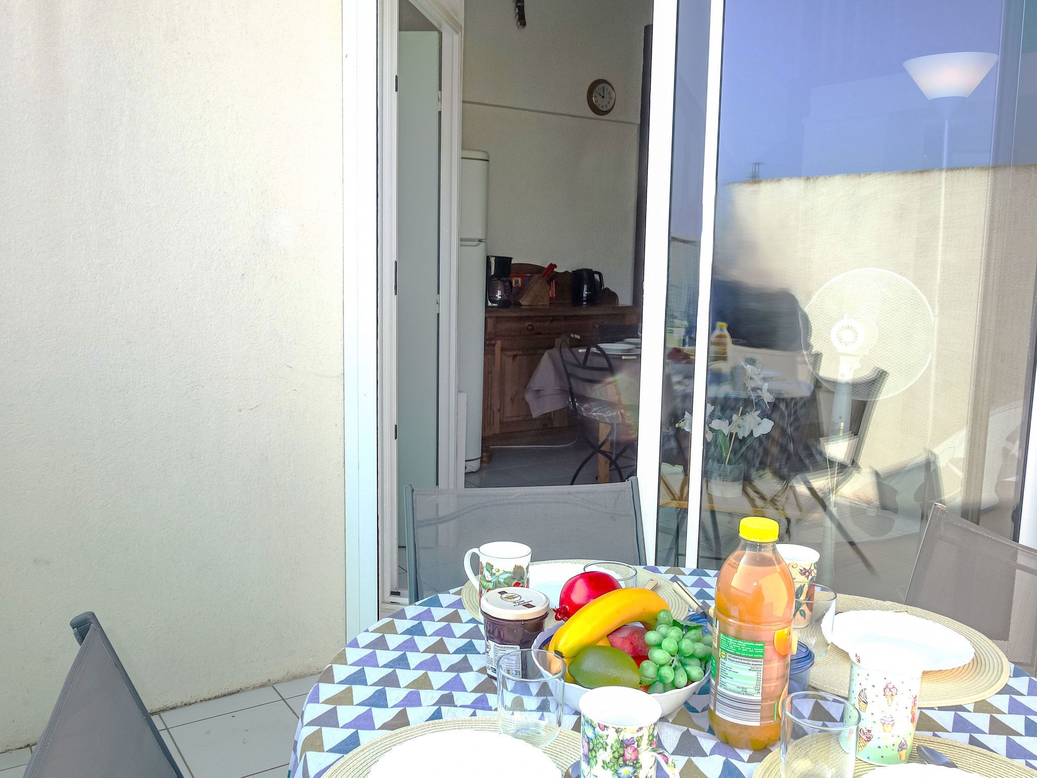 Ein Tisch mit Obstschale, Saftflasche und Tasse, drapiert mit einem gemusterten Tischläufer.