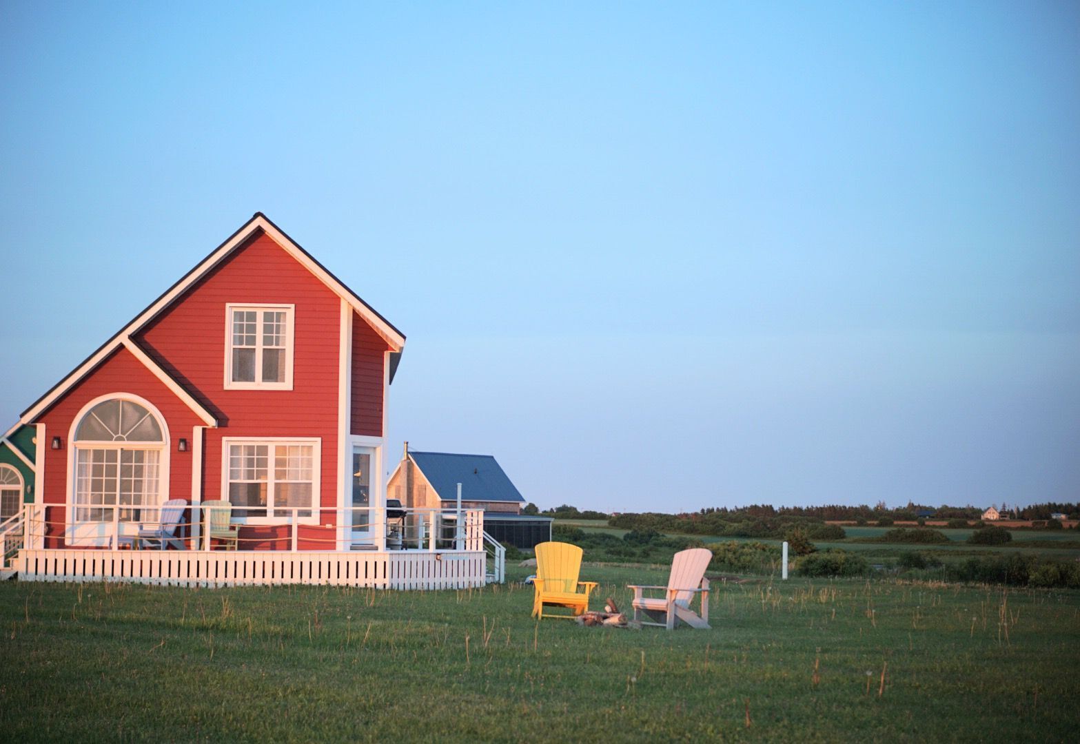 A red house with a porch and two Adirondack chairs.
