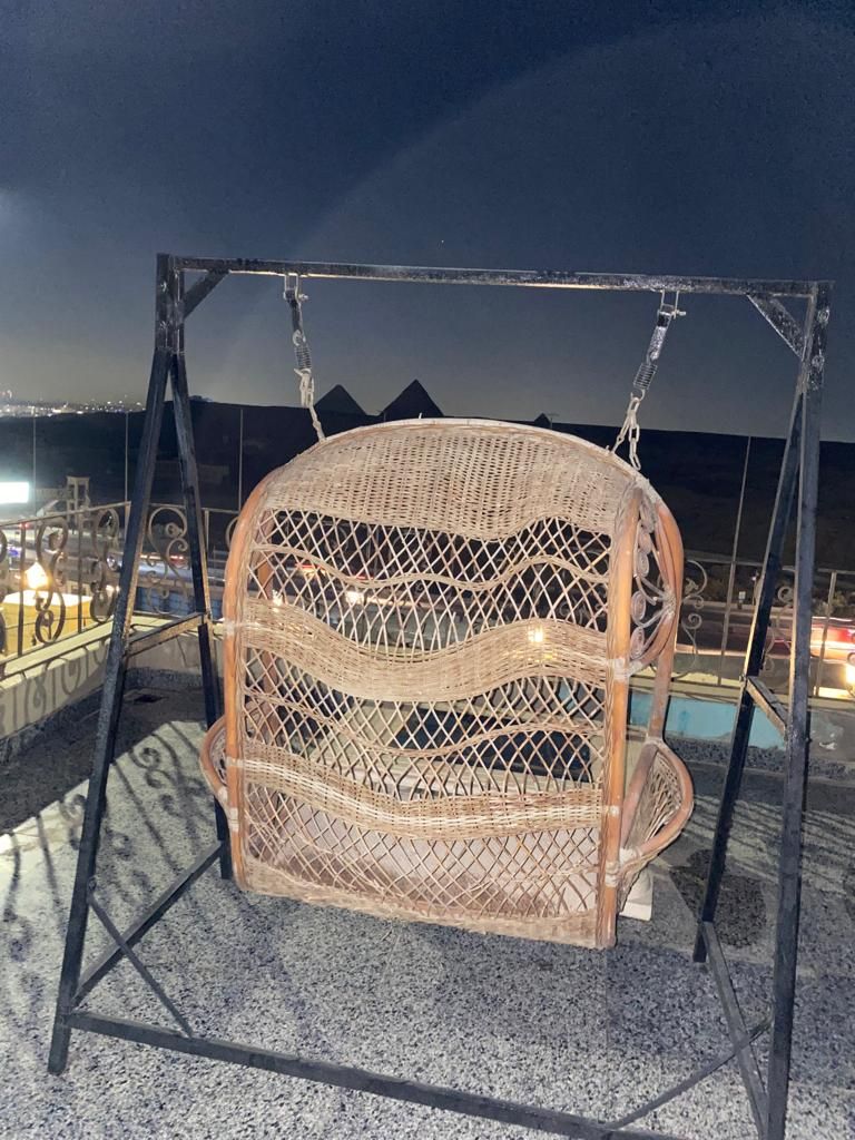 Una silla colgante de mimbre sujeta por una estructura metálica, probablemente al aire libre.
