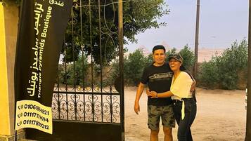 A man and a woman standing in front of a hotel entrance with a sign that reads 'TRIANGLE BOUTIQUE Hotel - de Paramus Boutique.'