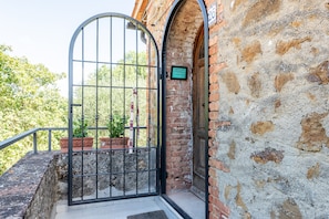 A wrought iron gate, a brick wall, and a door with a sign. - Apartment 'Villa Rosa' with Mountain View and Balcony (Torrita di Siena)